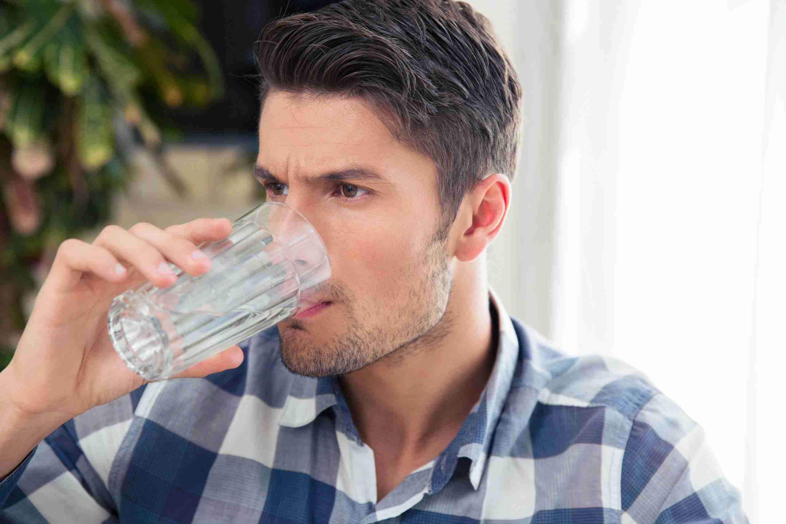 A man hesitantly drinking a glass of water