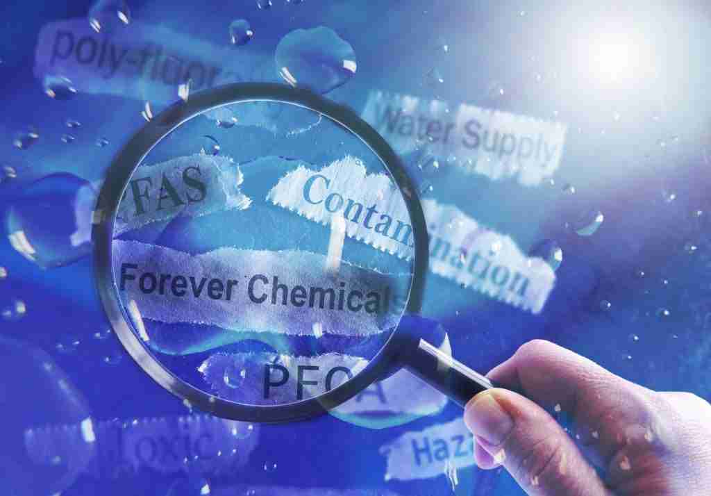 A magnifying glass held over strips of paper representing PFAS in drinking water.